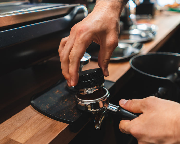 Behind the bar of a third wave coffee shop with Barista pressing some coffee
