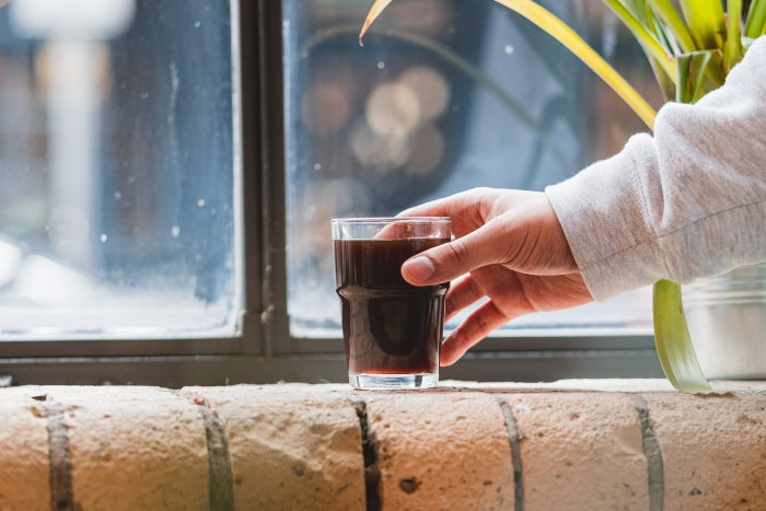 Customer at Hermanos drinking a glass of Colombian coffee after experimenting with different coffee roasts