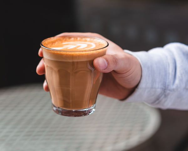 Customer holding latte made using decaf coffee beans