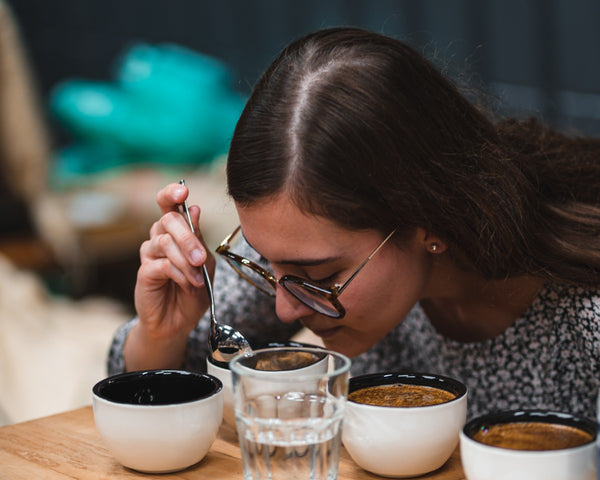 Girl in glasses smells coffee during coffee tasting experience