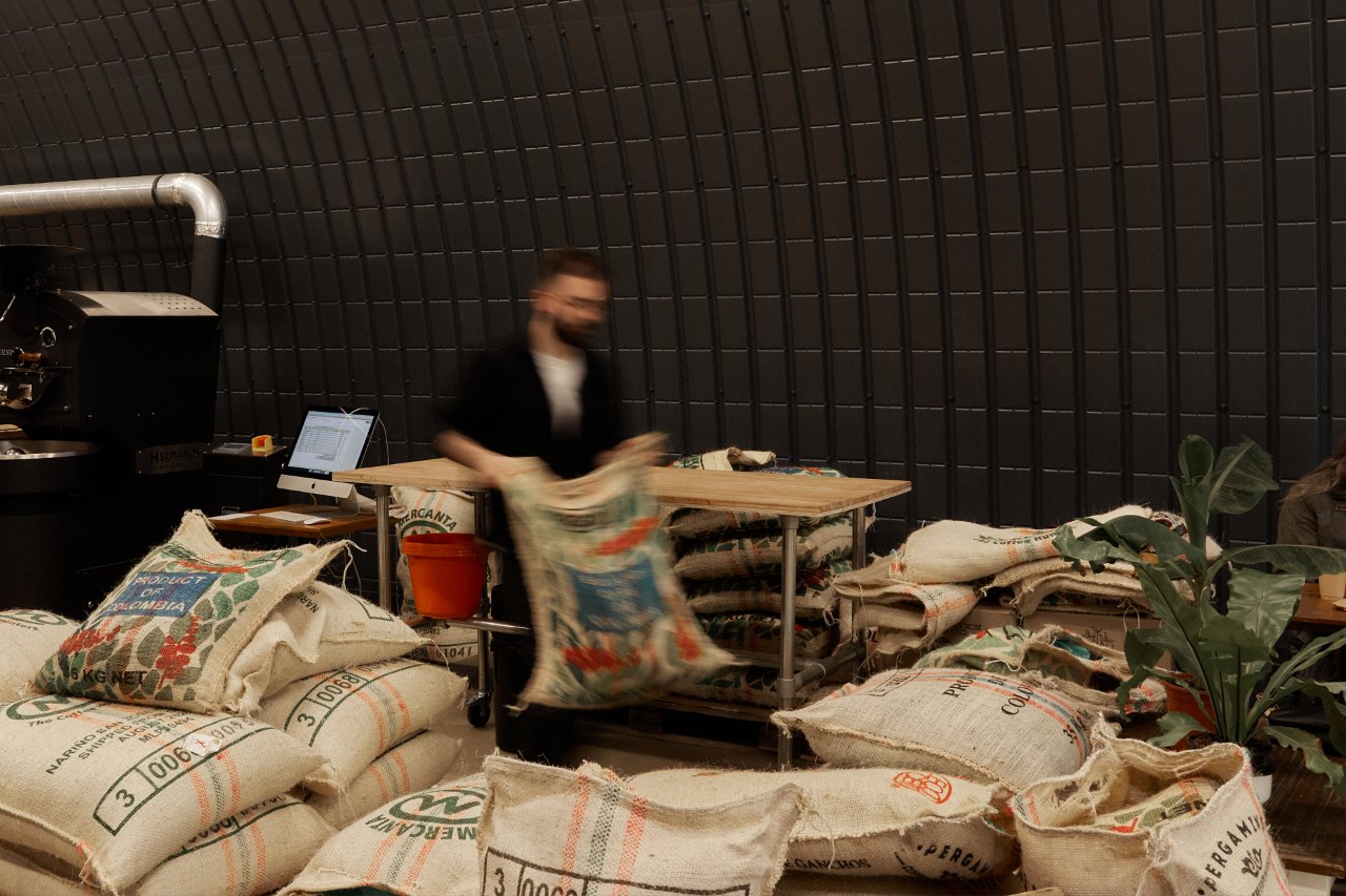 A specialty coffee roaster moving organising bean sacks in a roastery