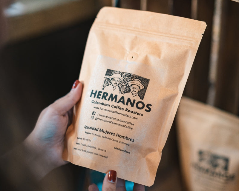 Woman holding a bag of Hermanos colombian coffee considering the cost of coffee